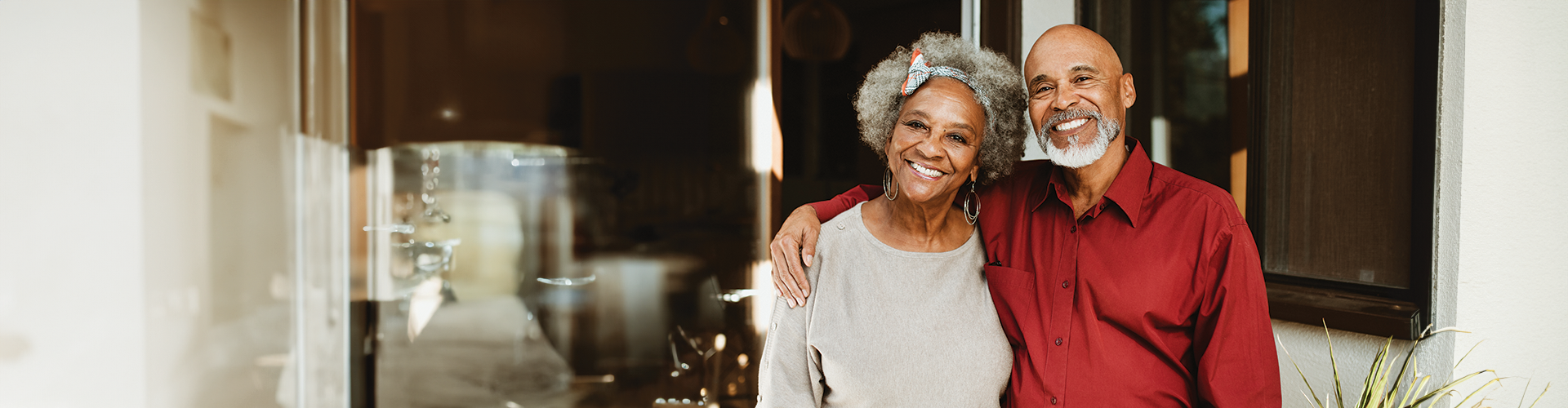 A smiling older couple standing together in a home entryway, showcasing a welcoming atmosphere.