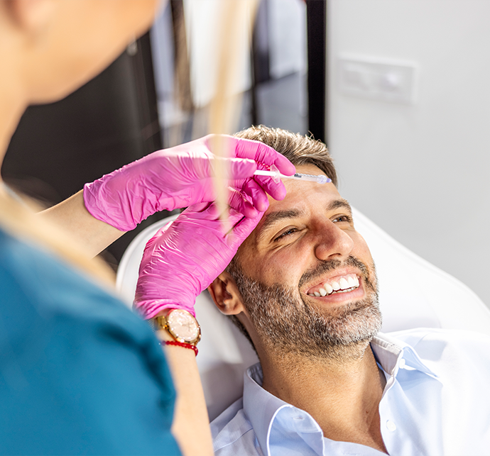 A dentist applying a treatment to a smiling male patient in a modern dental office.