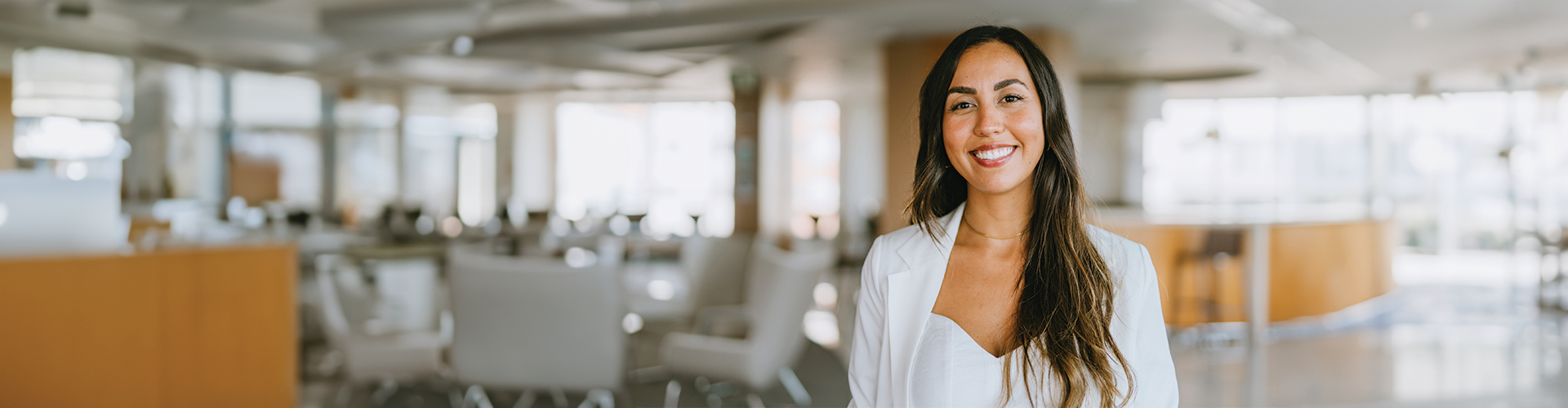 A smiling woman in a white coat stands in a modern dental office with a bright and welcoming atmosphere.
